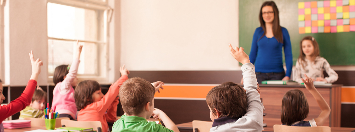Children in elementary school are raised hand in classroom